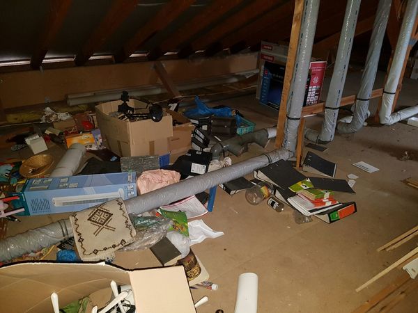 Dachboden mit verschiedenen Kartons, Aktenordnern, Rohren und Haushaltsgegenständen voller Unordnung.