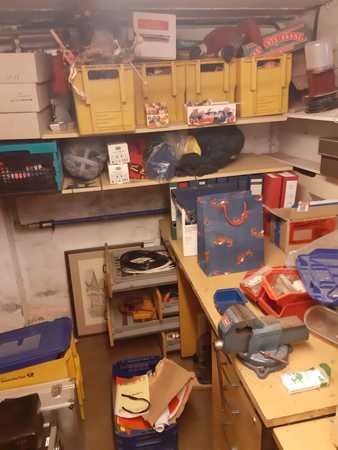 Kellerraum mit Werkbank, Regalen, Werkzeugen, Kisten und verschiedenen Utensilien.